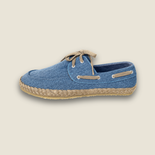 A single blue denim espadrille shoe with beige laces and a braided jute sole, shown from a side profile on a light beige background.